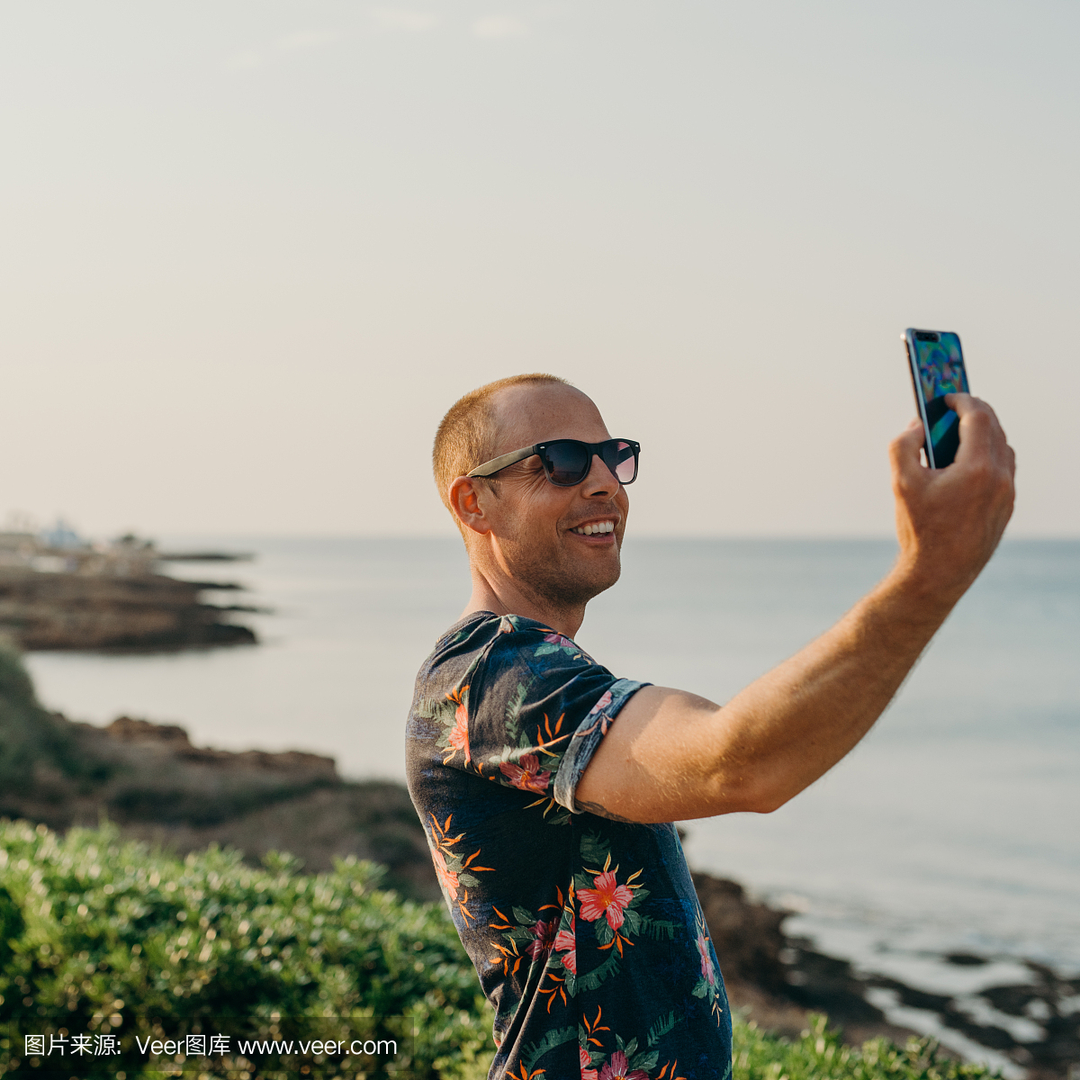 假期的男人用智能手机拍照或自拍
