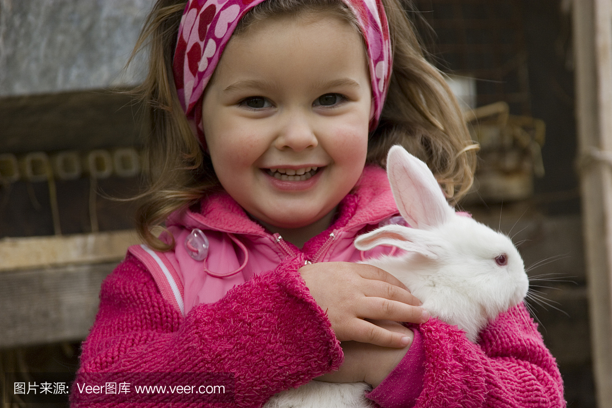 粉红色的小女孩抱着一只白色的兔子