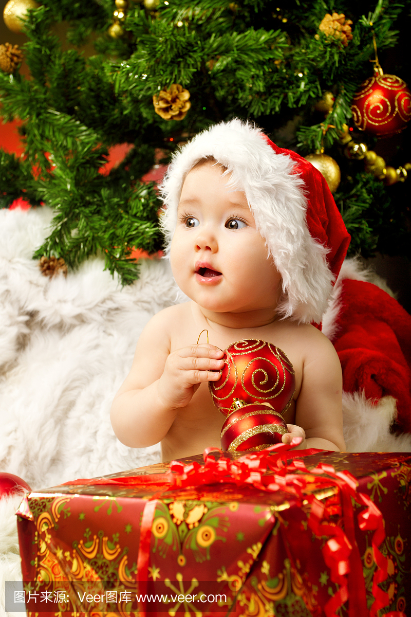 圣诞婴孩的帽子拿着红色的礼物