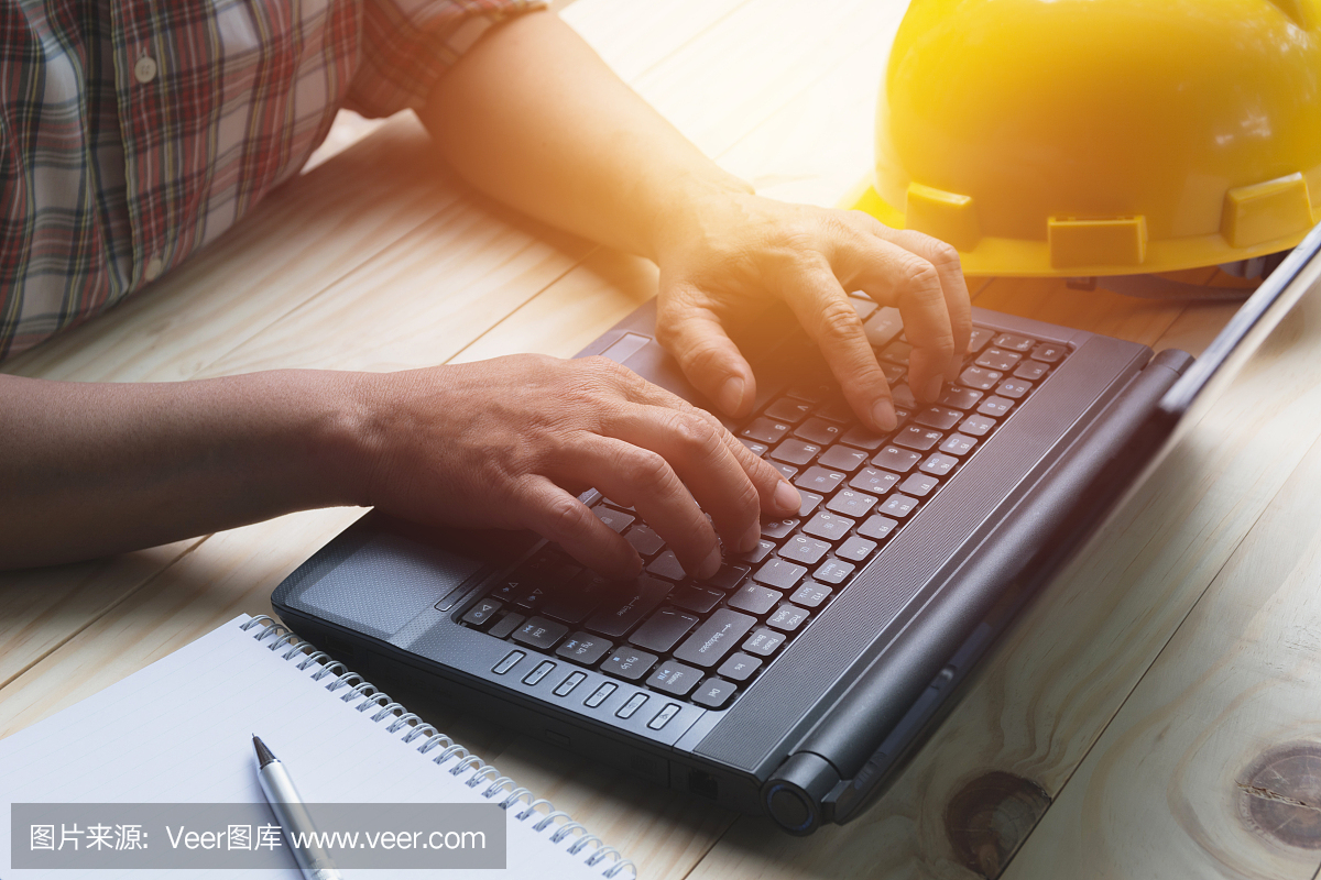 建筑师工程师使用笔记本电脑与桌上的黄色头盔