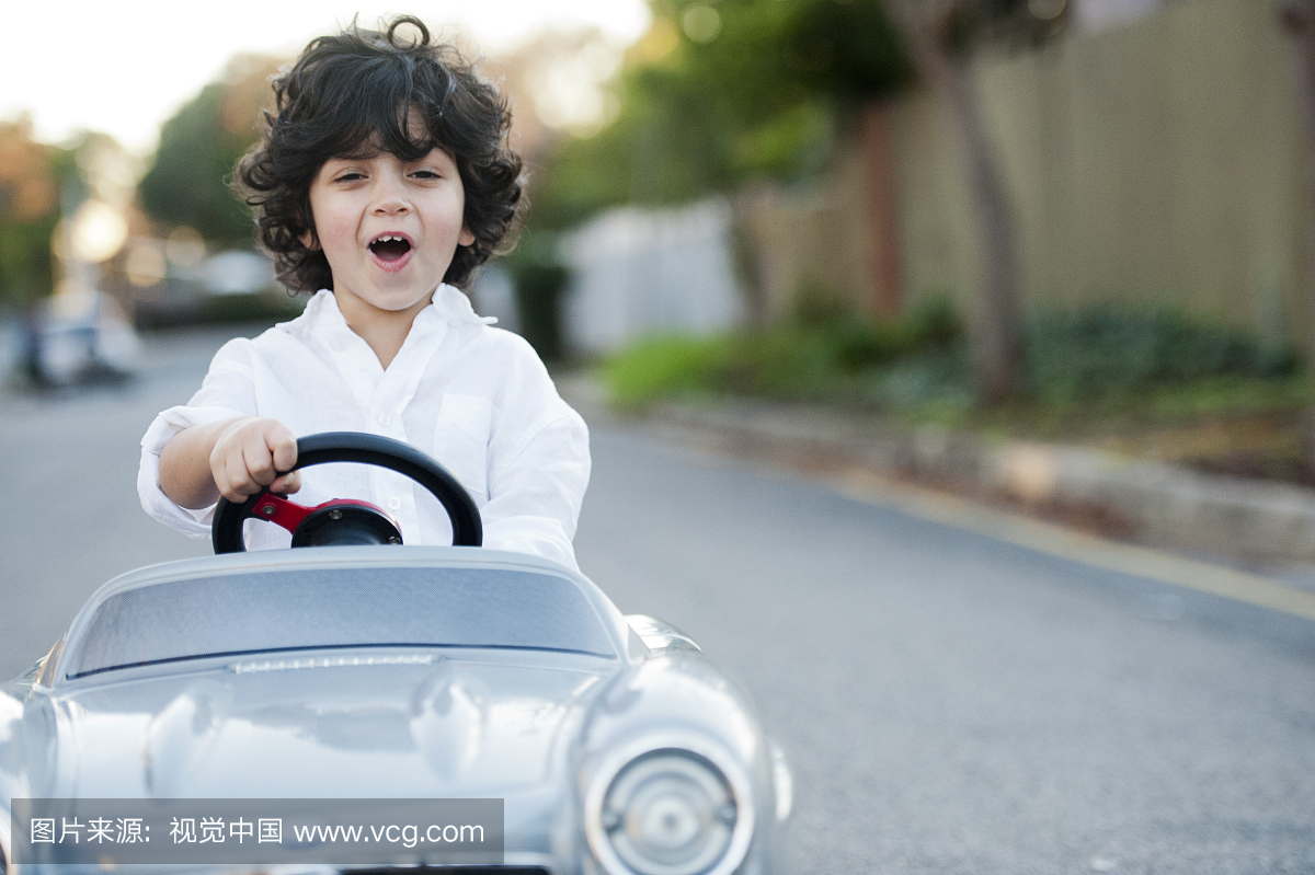 Portrait of young boy ( 2-3 ) driving toy car