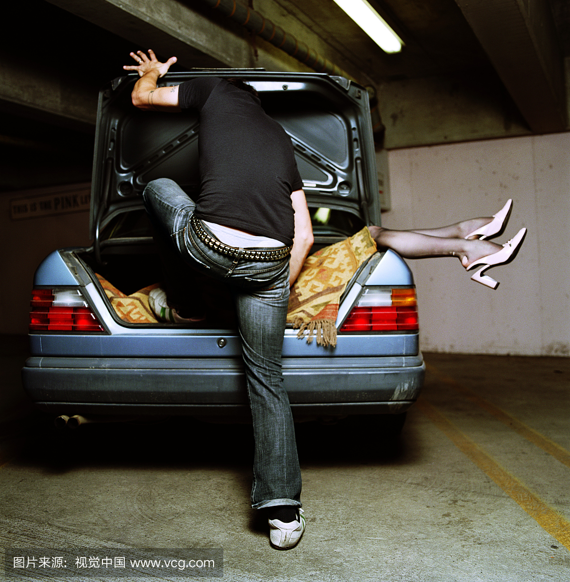 男子踩在毯子上的女人,躺在汽车后备箱