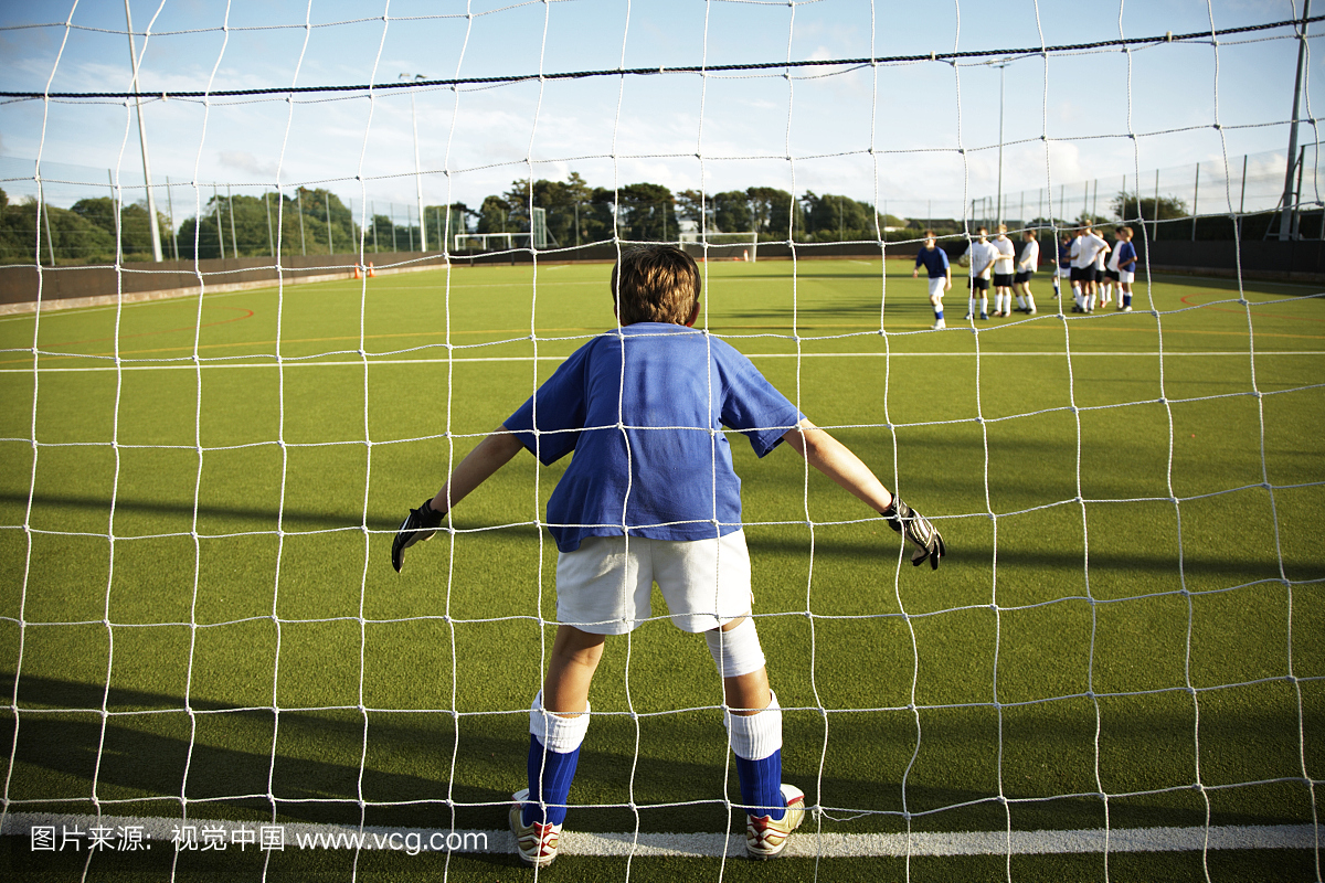 男孩(9-11)准备作为足球场的守门员,后视图