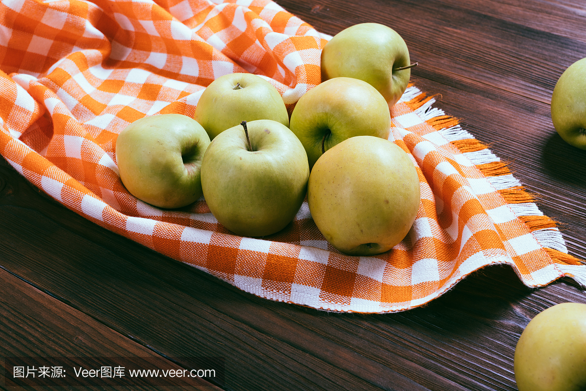 绿色的苹果在一个木制的桌子和橙色的桌布上