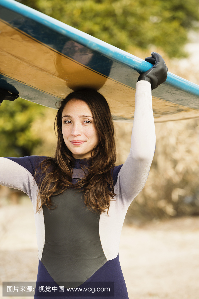 西班牙裔冲浪运动员在海滩上运载板
