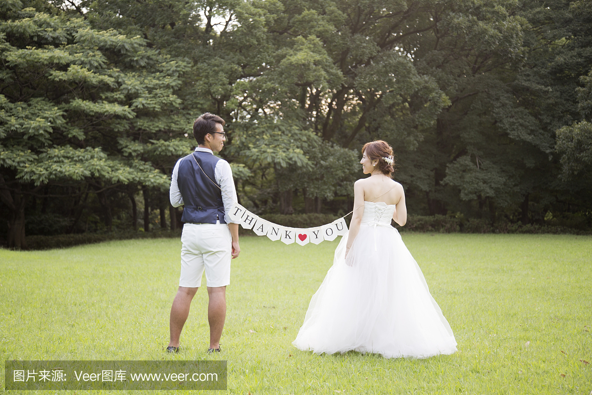 新娘和新郎穿着婚礼服装,拿着标志与消息在公