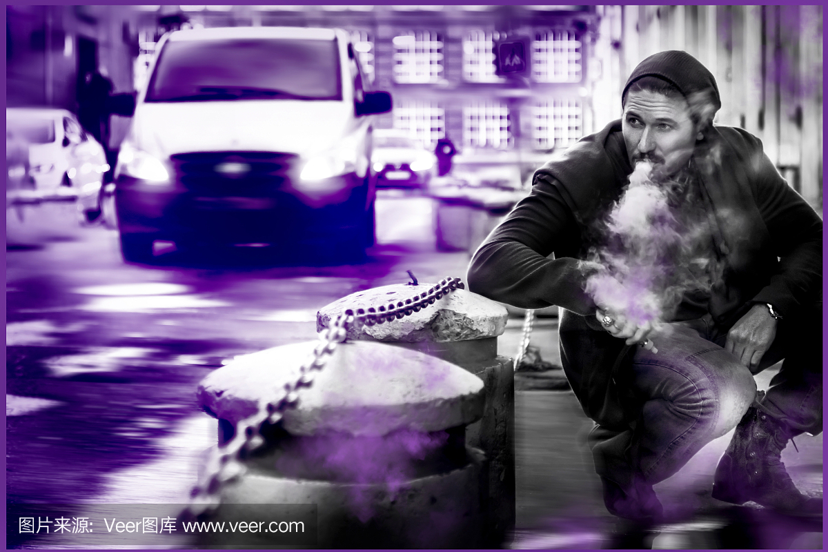 男子在大城市的街道上抽电子烟。 Vaping。紫
