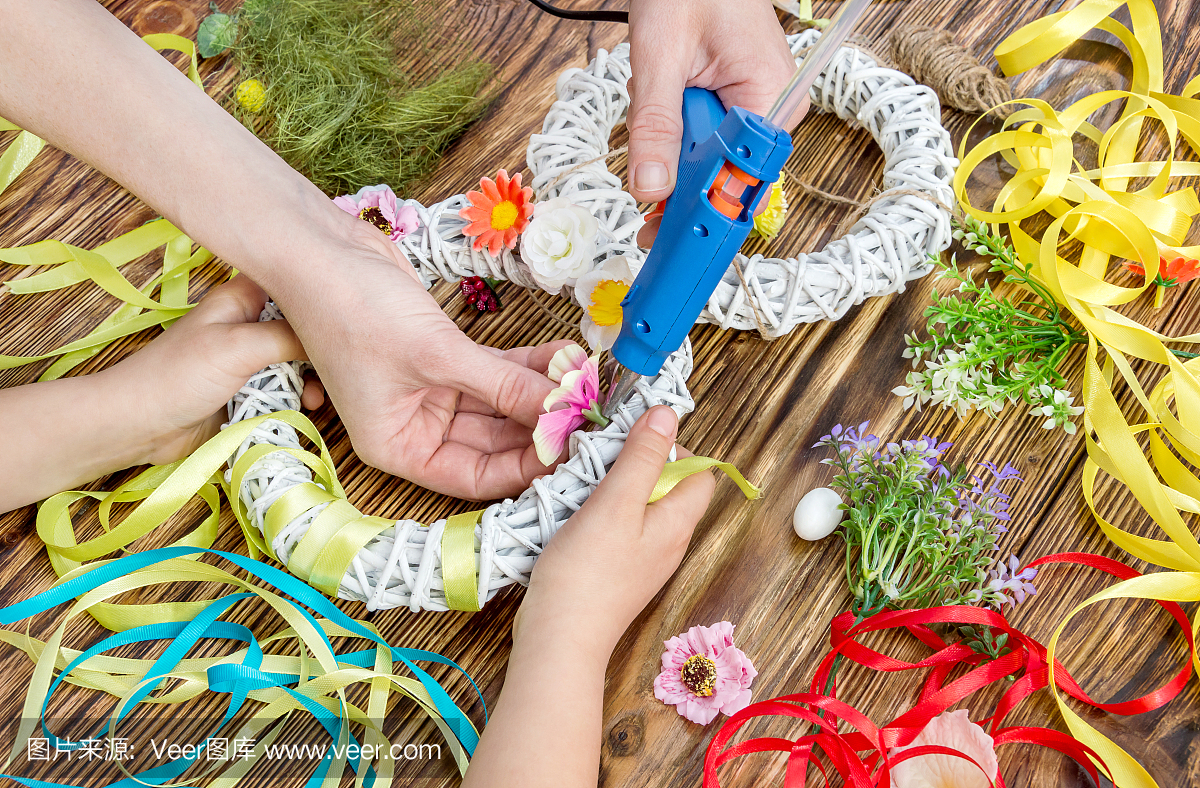 母亲和她的女儿用胶枪制作手工花卉装饰品。