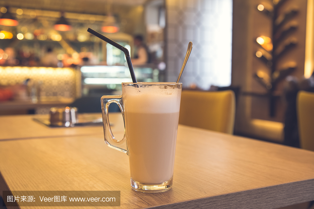 关闭玻璃杯咖啡加牛奶放在咖啡厅的桌子上