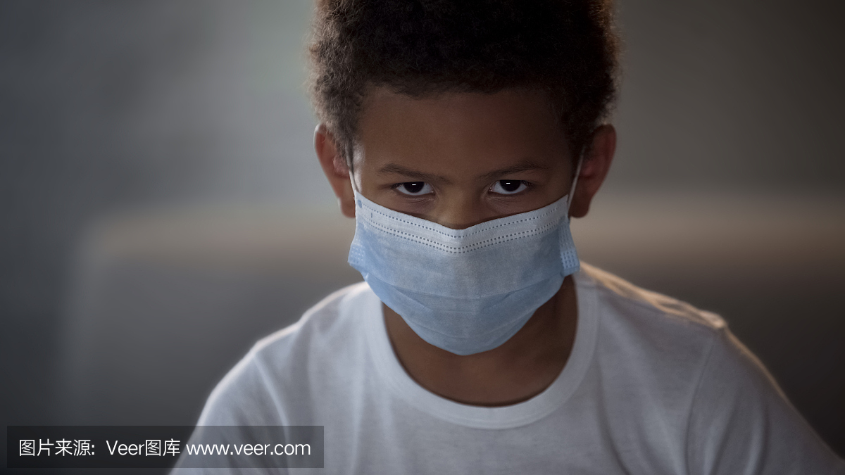 非洲裔美国孩子在医疗面具看着相机与悲伤的眼