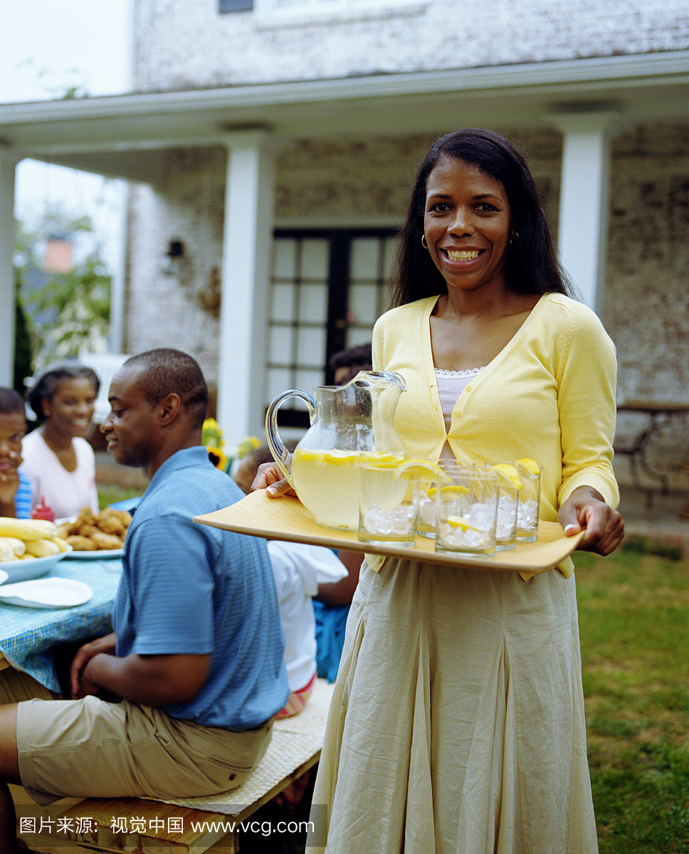 在后院的妇女携带托盘的柠檬水,微笑的肖像