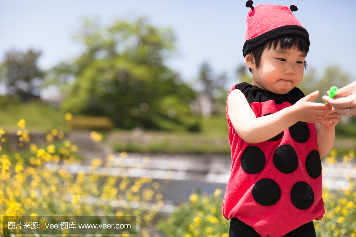 在瓢虫衣服上飞过花园的日本女婴