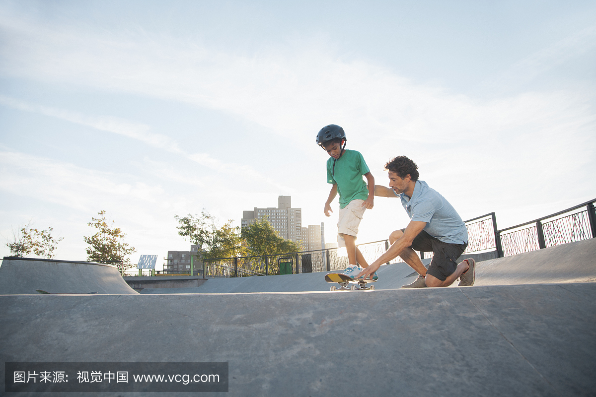Man teaching son (10-12) skateboarding