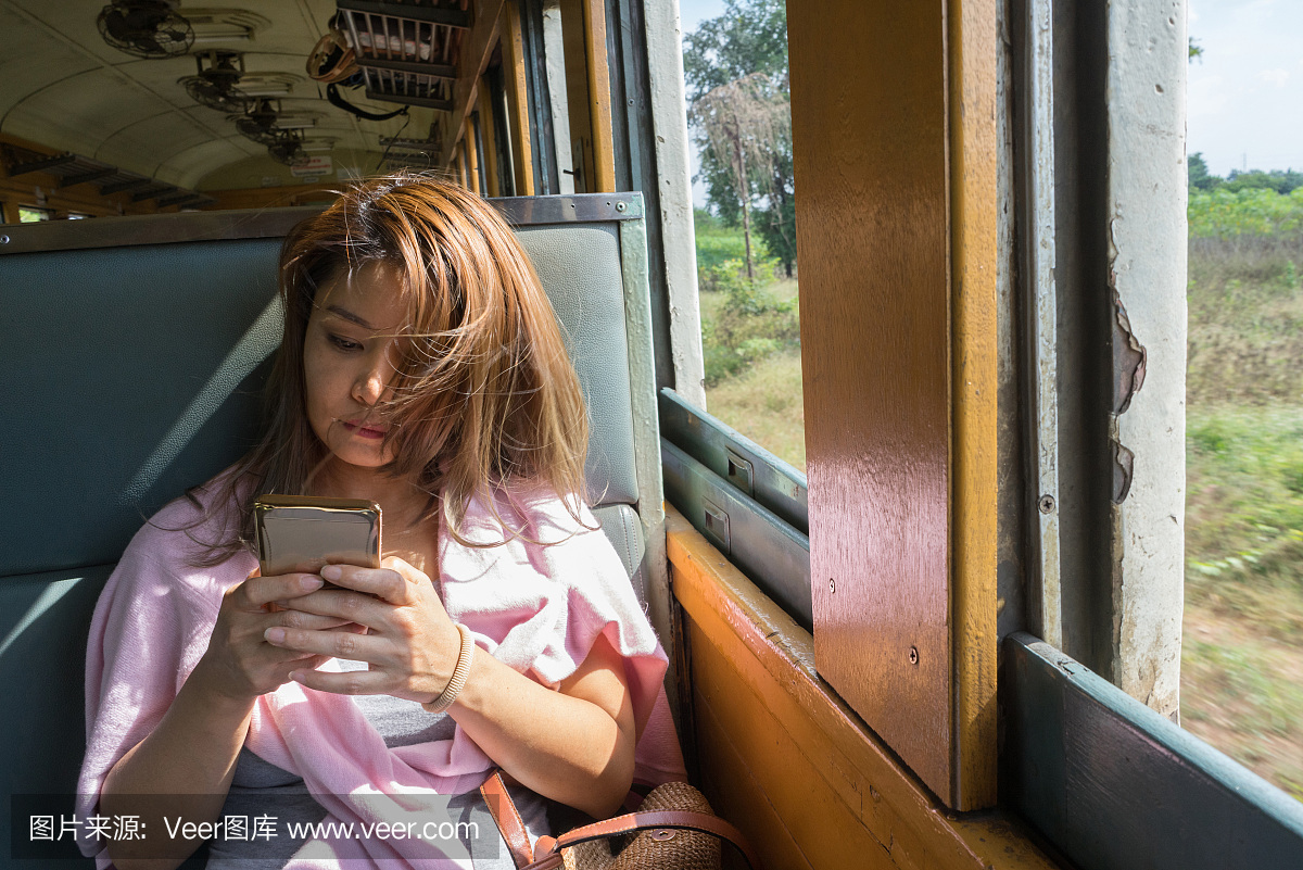 看着移动火车上的手机的泰国女人