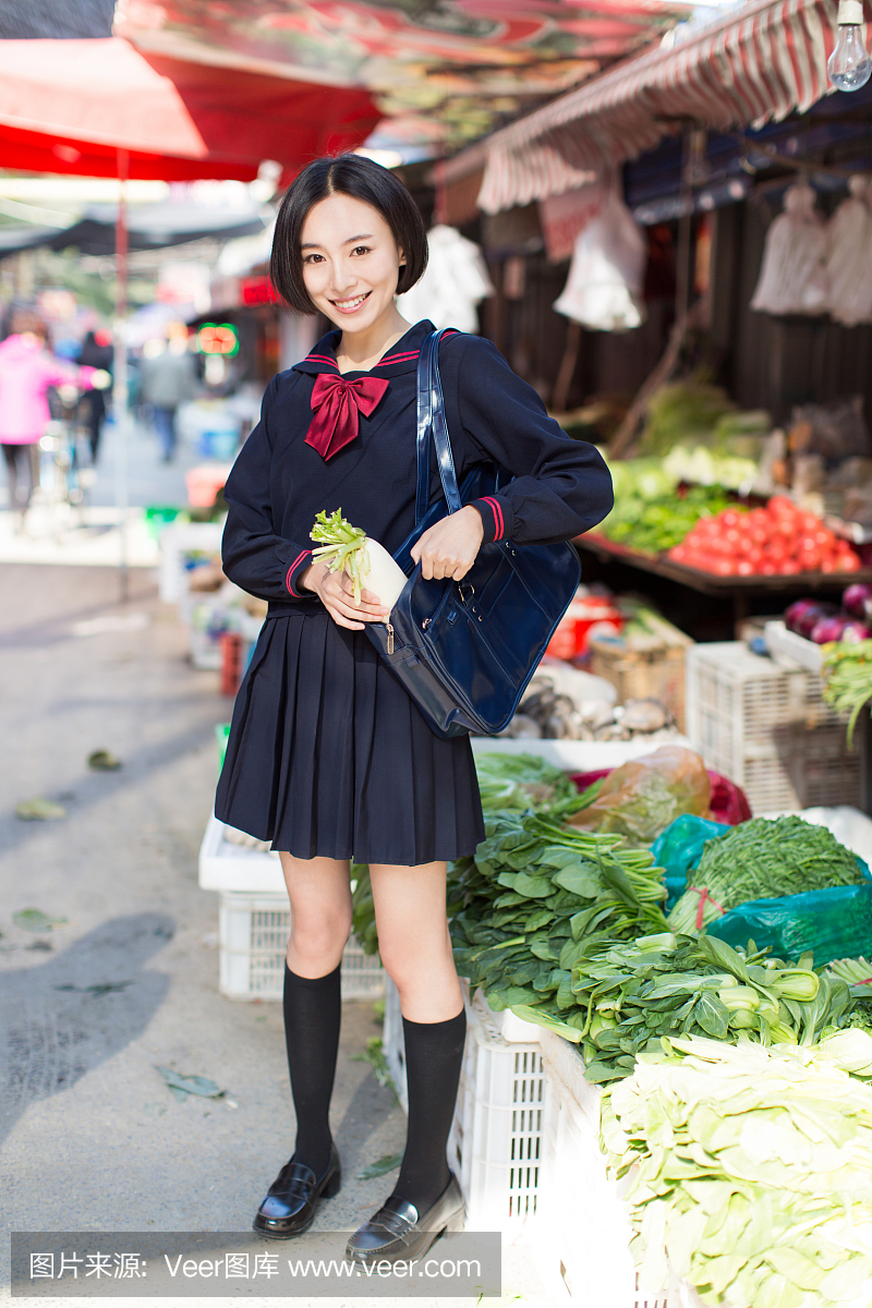 美丽的中国女学生在市场上买水果和蔬菜