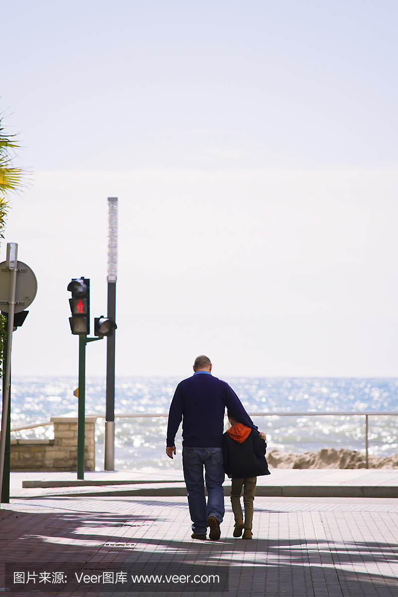 男孩与他的父亲走在海边的城市西班牙萨洛