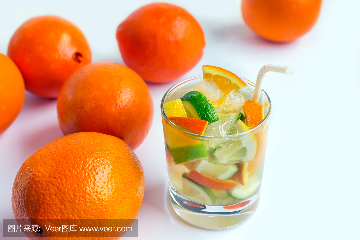 杯苏打水饮料切片的柠檬,橙和石灰在多汁的桔子旁边的白色背景上。概念 - 健康食品,健身,排毒。