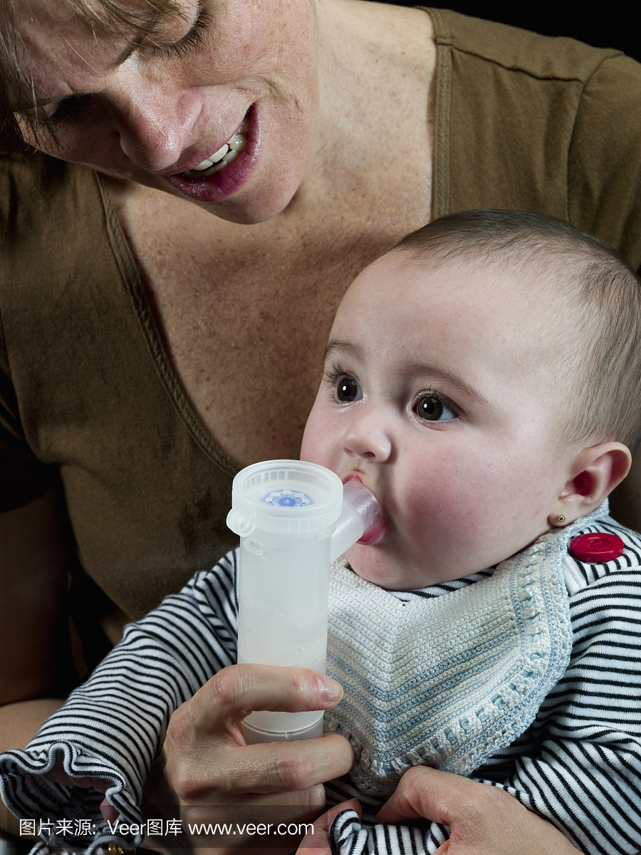 一个婴儿在妈妈的帮助下使用雾化器