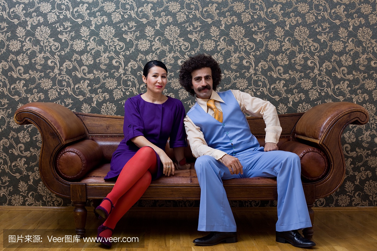 年轻夫妇在20世纪70年代风格的衣服坐在真皮