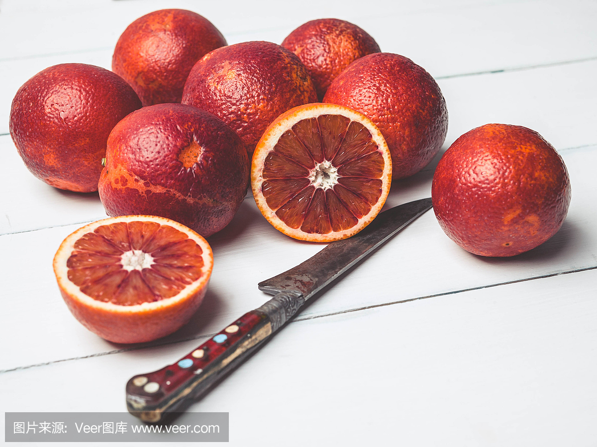血橙和白色的木制背景上的刀。季节性柑橘类水