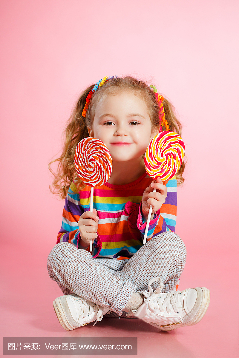 一个快乐的小女孩与棒棒糖的工作室肖像