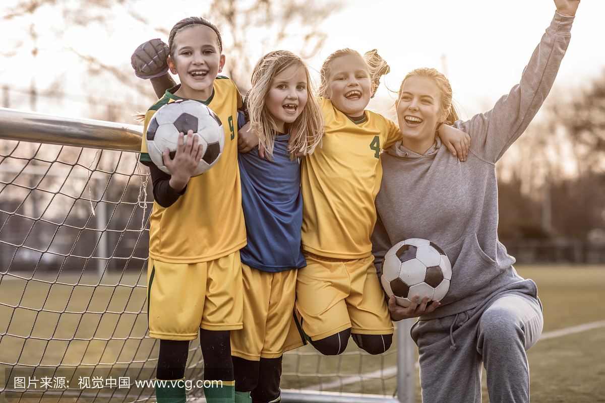 年轻的金发女子足球教练和她的女孩足球队
