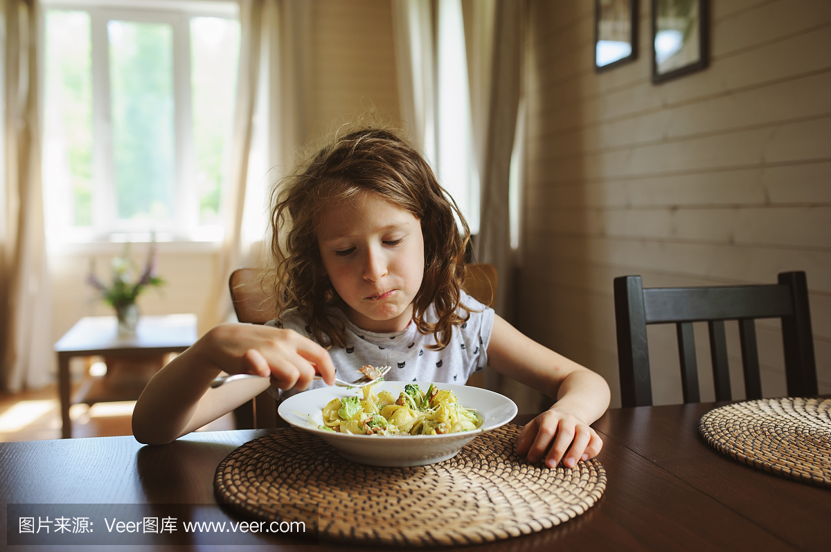 8岁快乐的小孩女孩在家吃午餐或晚餐的面食