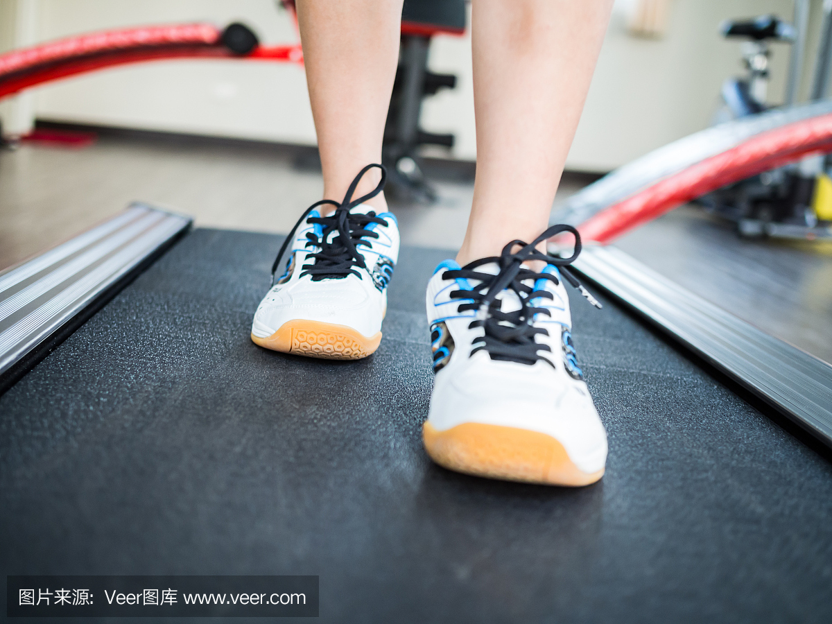 女孩跑在跑步机上。关闭在腿上的射击。
