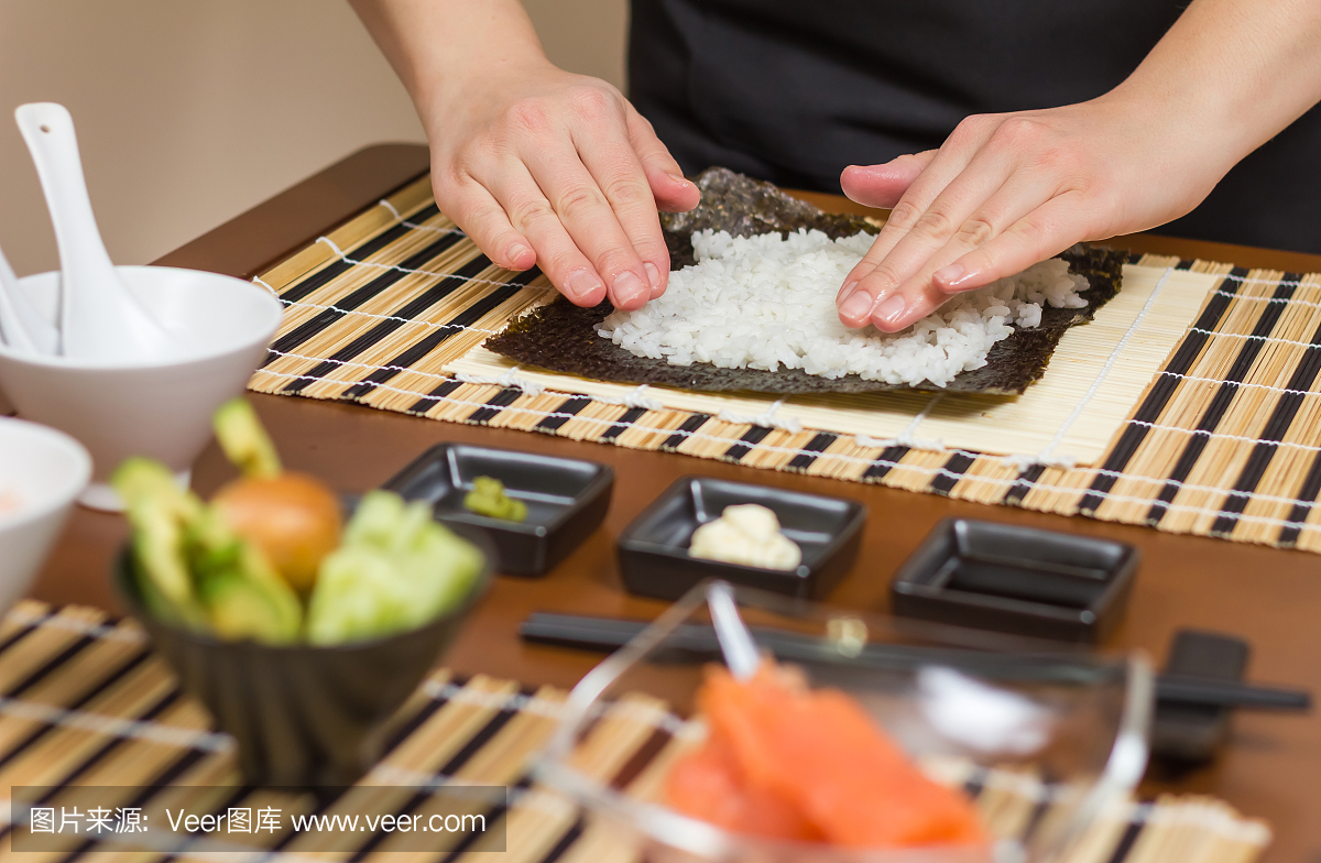 女士厨师用米饭填充日本寿司卷
