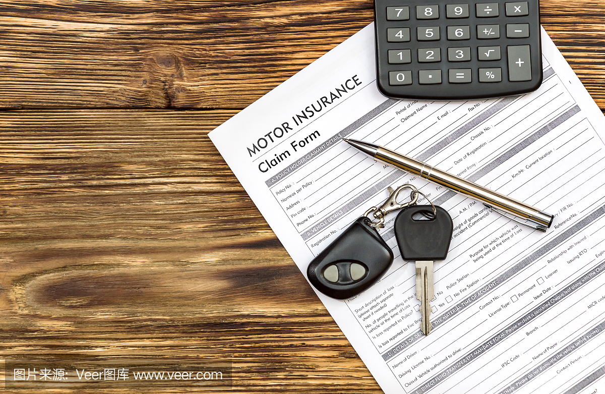 汽车保险单与汽车钥匙,笔和计算器在桌子上。
