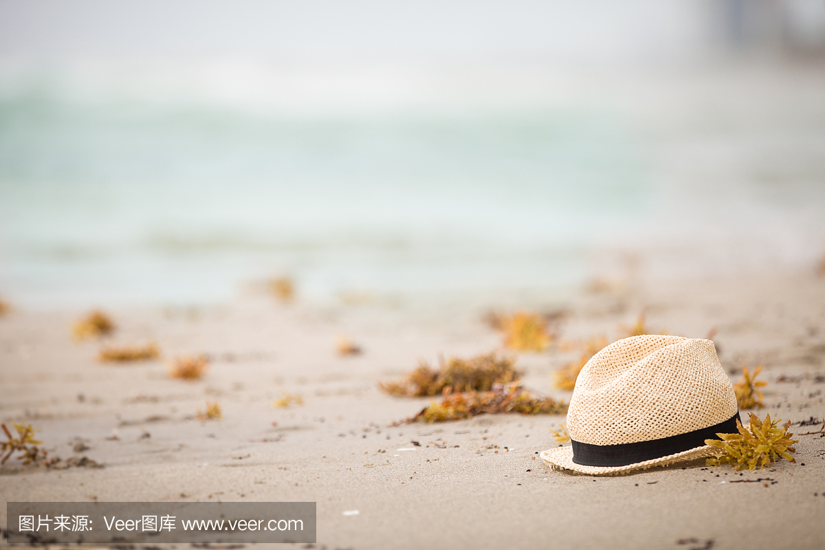 漂亮的草帽躺在沙滩上。美丽的海洋海滩背景。