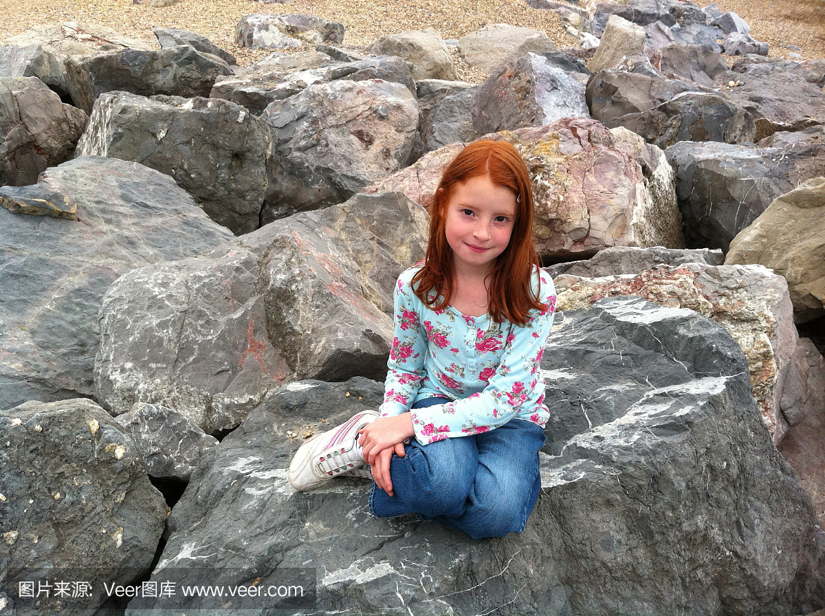 女孩在小美人鱼姿势在岩石上的形象
