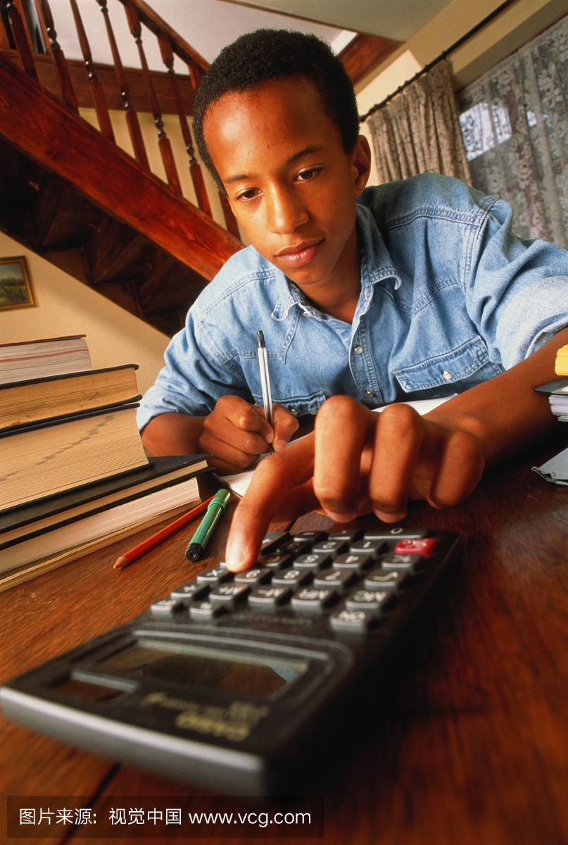 十几岁的男孩(12-14)做家庭作业,使用计算器,特