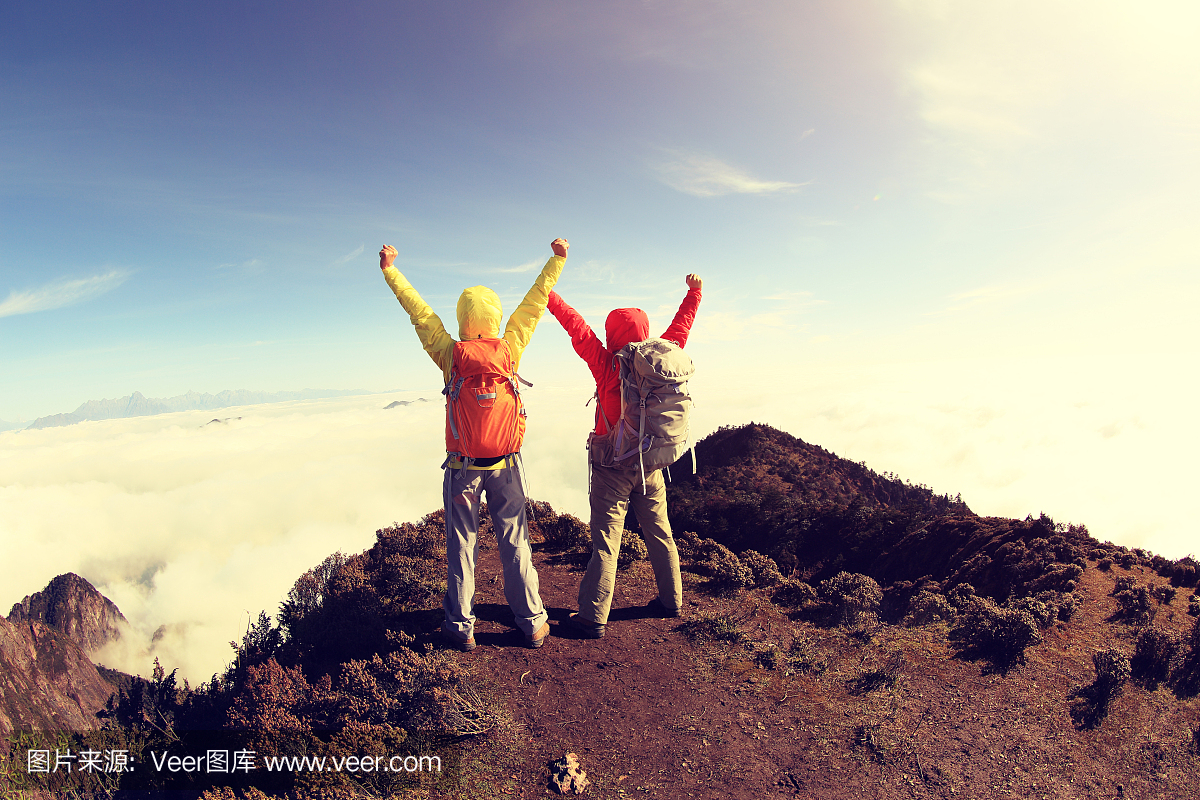两个成功的徒步旅行者在美丽的滚动云山峰