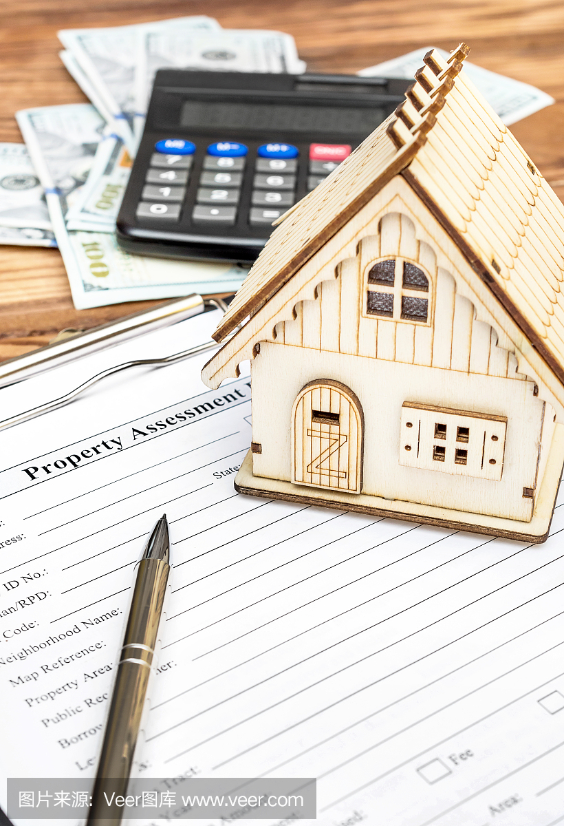 财产评估表与金钱,计算器和房子的模型在桌上