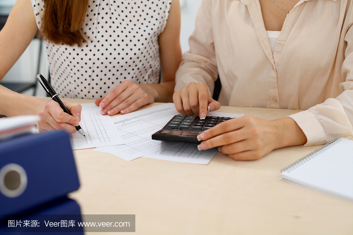 两名女性会计师指望计算器收入纳税表完成手特