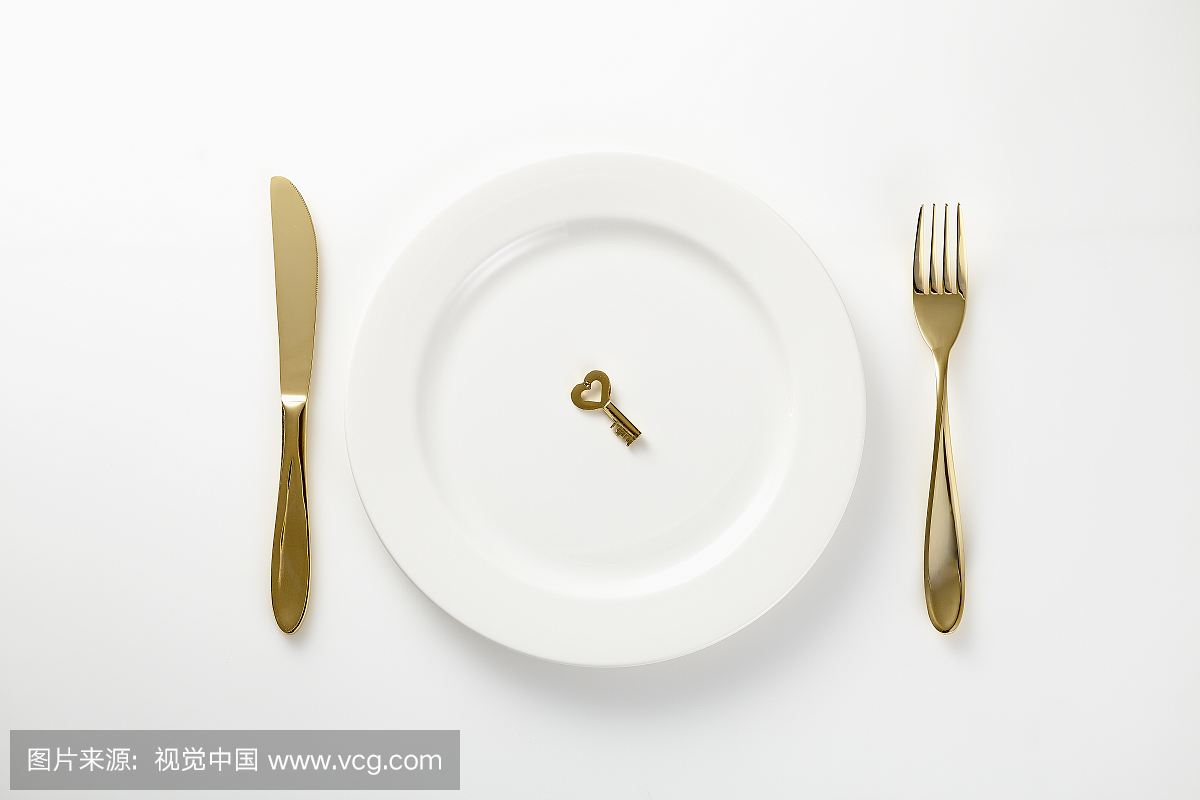Gold key on plate with knife and fork beside