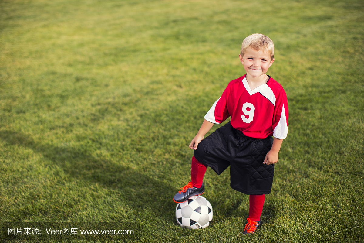年轻男子足球运动员站在草地上