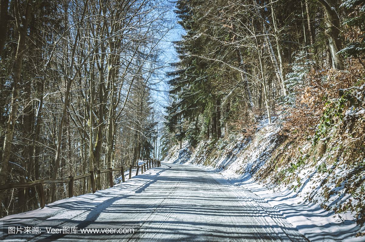 危险的冬季道路被冬季森林覆盖