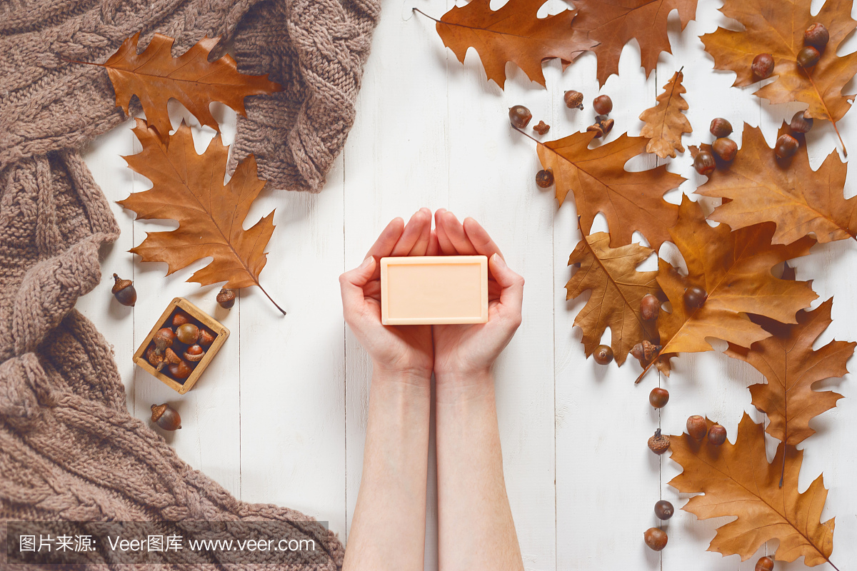 肥皂色的女性手中的一块肥皂与柔软的围巾和橡