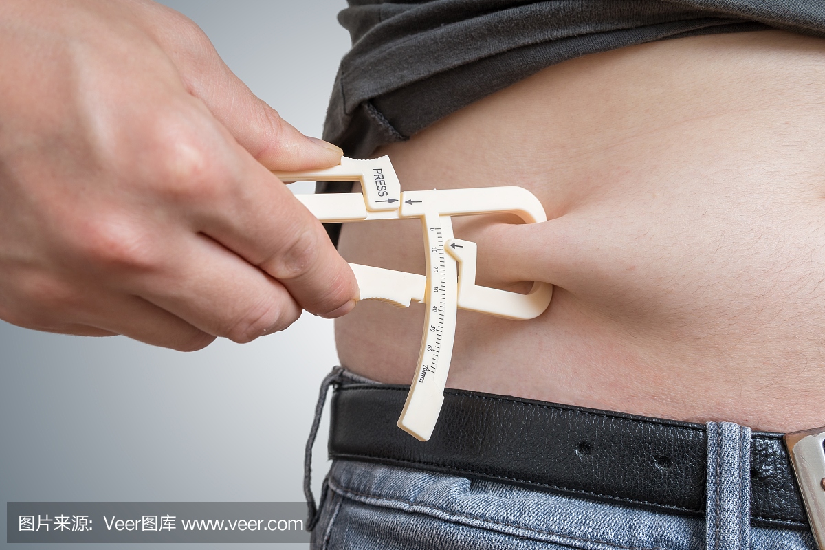 男人用卡尺测量他的肚子上的身体脂肪。