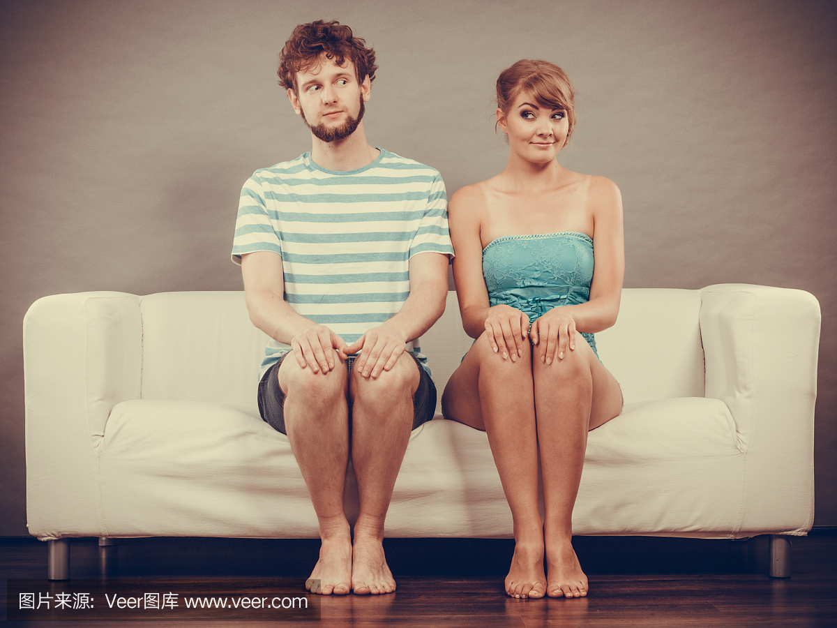 害羞的女人和男人坐在沙发上互相靠近。