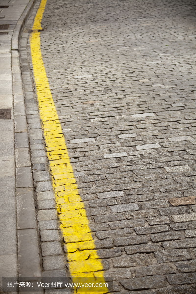 路边和黄线在鹅卵石街上。