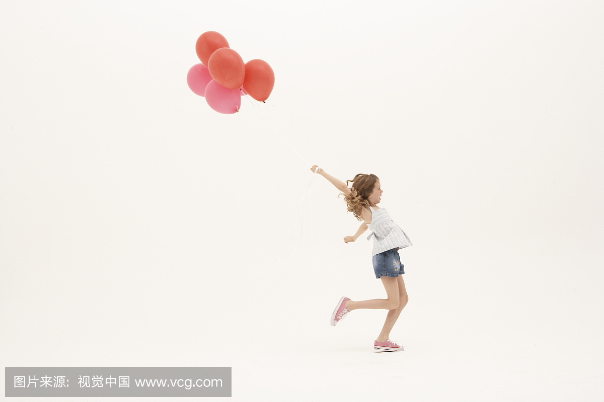 女孩(8-10)与一群气球跑,手臂抬起,侧视图