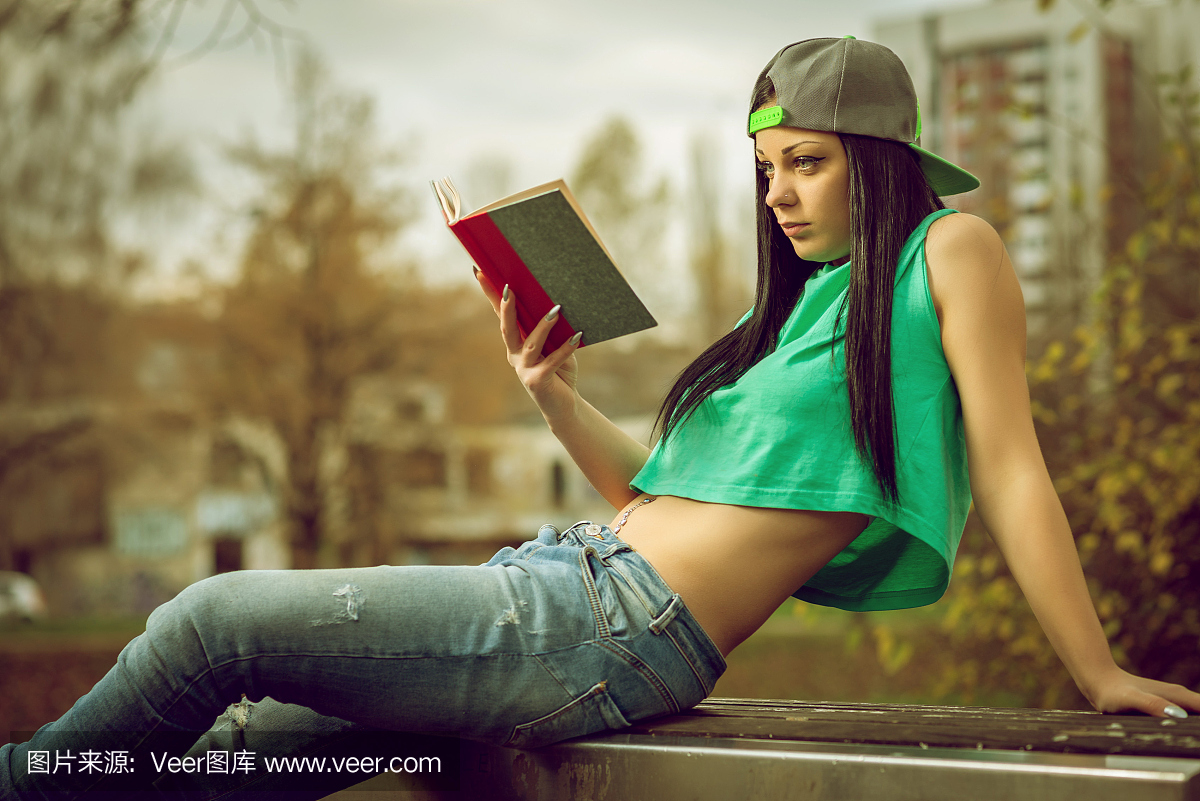 牛仔裤的女孩在长凳上看书