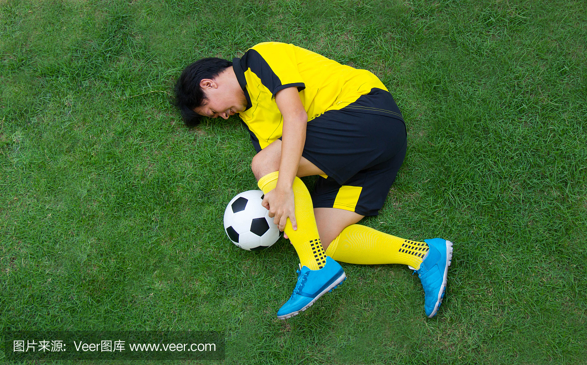 黄色的足球运动员在场上受伤。
