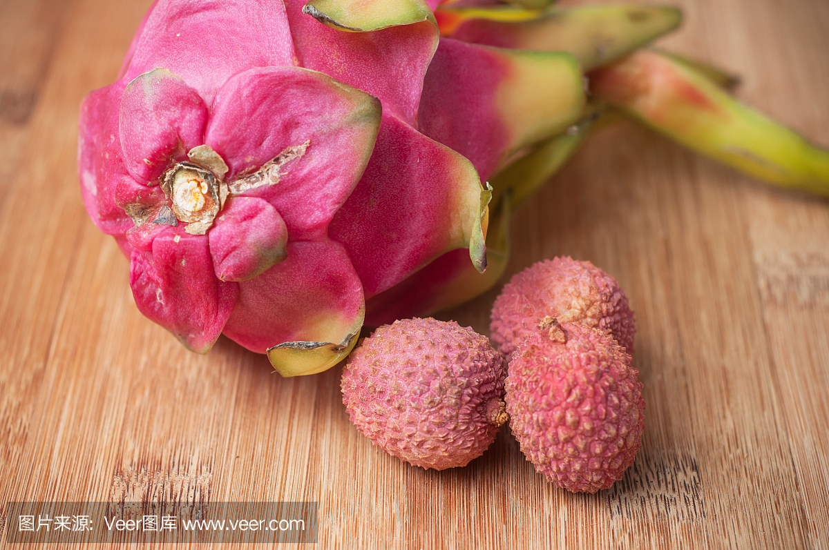 荔枝和火龙果果实在木质切菜板上竹纹理