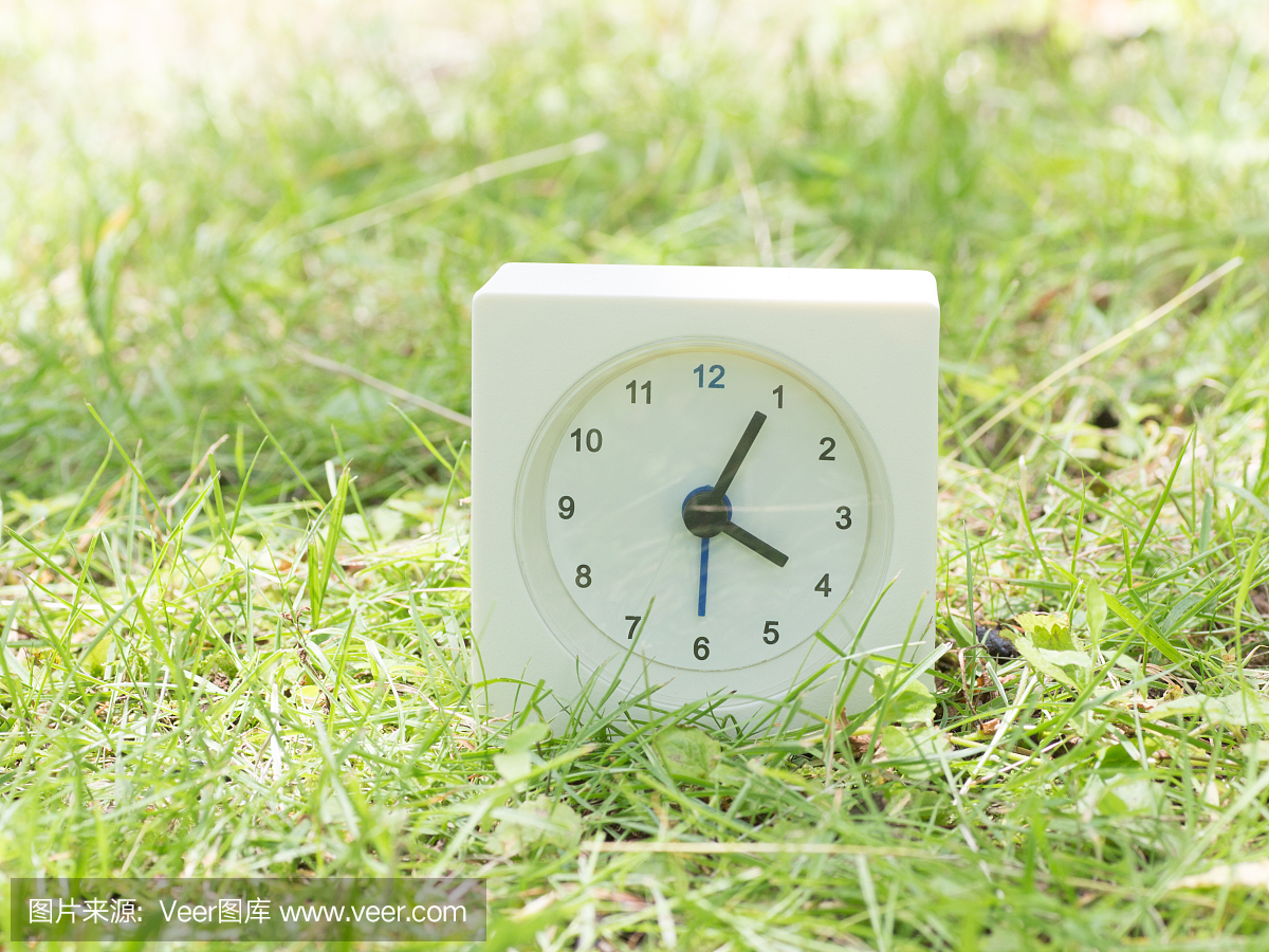 白色简单的时钟在草坪上,4点05分四点五点