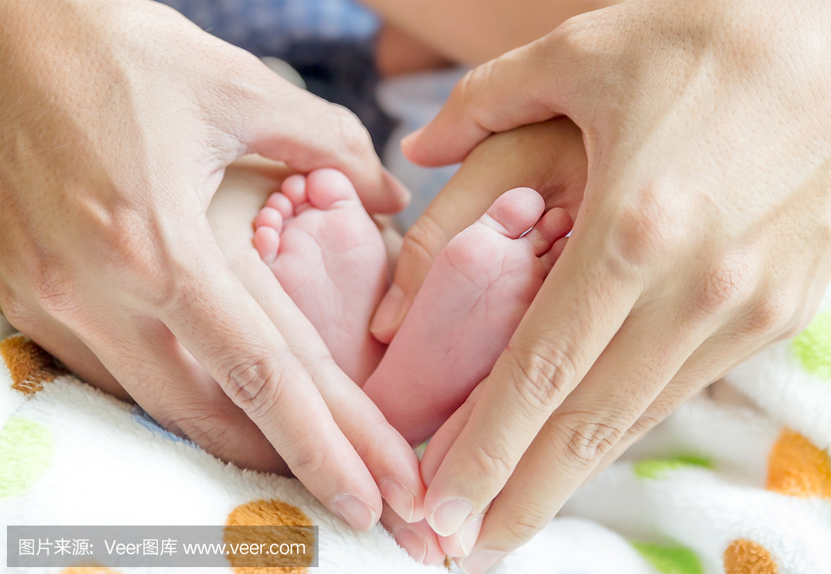 新生婴儿的脚在妈妈和爸爸手上,形状像一个可