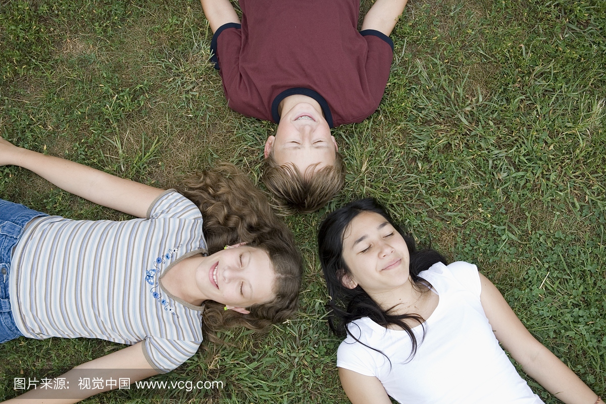 两个女孩和男孩躺在草地上的高角度视图
